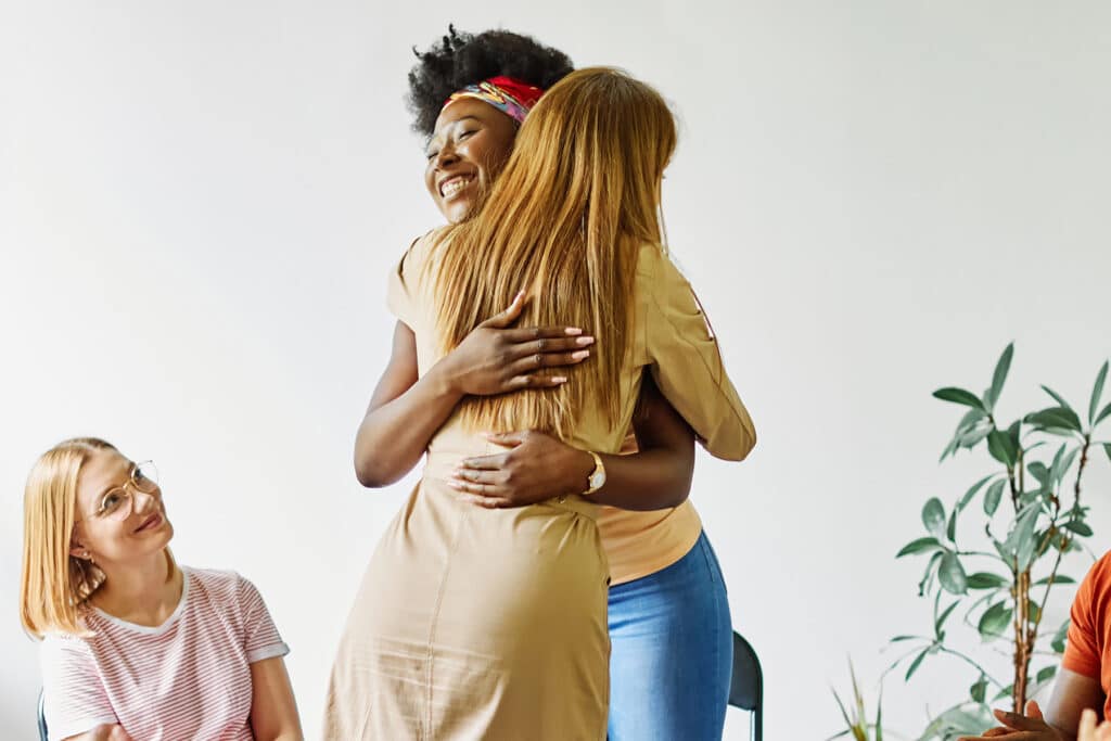 Two group therapy participants hugging