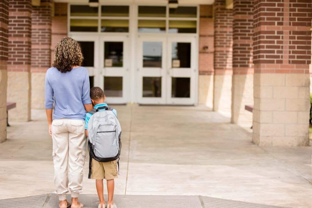A mother holding her son's hand on the first day of school