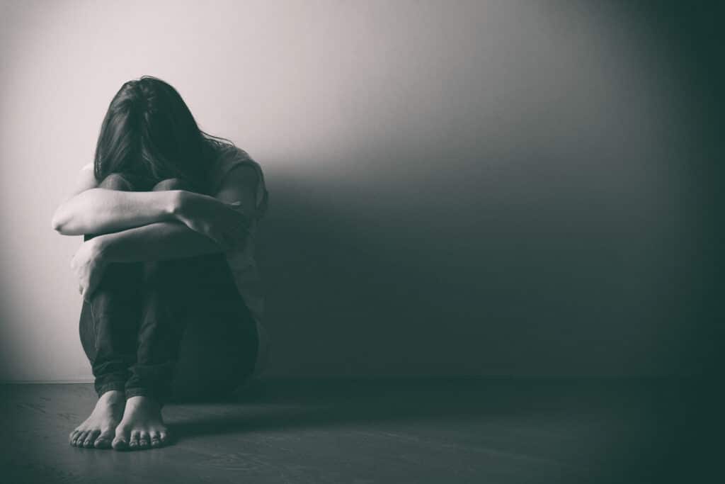 girl sitting alone on the floor in a dark room